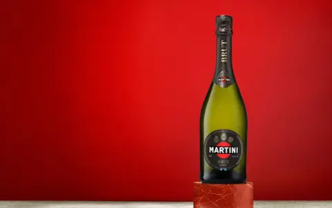 Butelka Martini Brut 7.5% alc. vol. na tle czerwonej ściany.