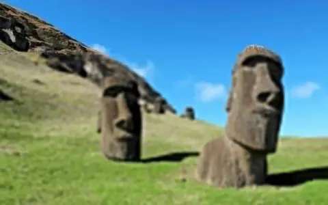Kamienne posągi Moai na zielonym wzgórzu. To słynne miejsce, które przypomina, do jakiego państwa należy Wyspa Wielkanocna.