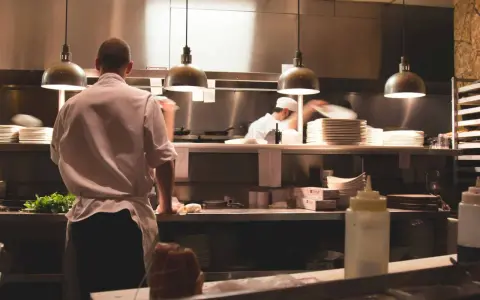 Kucharz w białej koszuli i fartuchu pracuje w kuchni restauracyjnej. To idealne miejsce, by napisać list motywacyjny kucharz.