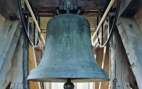 Große, grüne Kirchenglocke im Glockenturm, bereit zum Läuten an Ostern.