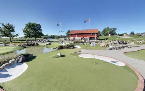 En solig dag på slussen minigolf i Sverige. Grönskande banor, vattenhål och stenar skapar en utmanande och rolig miljö.