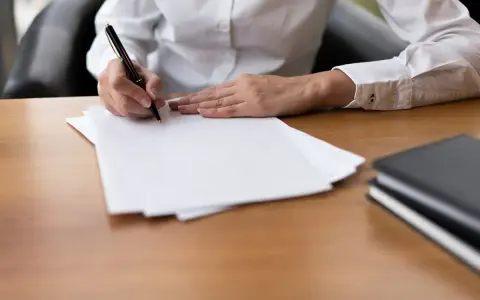 Ręka pisze piórem na białej kartce. Czy to umowa cywilnoprawna?