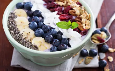 Miseczka pełna super foods: jagody, banany, nasiona chia, płatki kokosa, żurawina i granola. Idealne śniadanie.