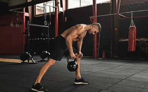 Mężczyzna wykonuje trening funkcjonalny ćwiczenia z kettlebell w siłowni.