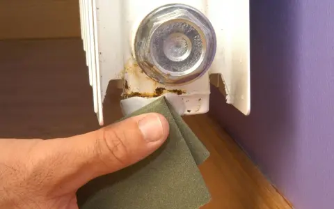 Lijando la zona oxidada de un radiador para prevenir una fuga.