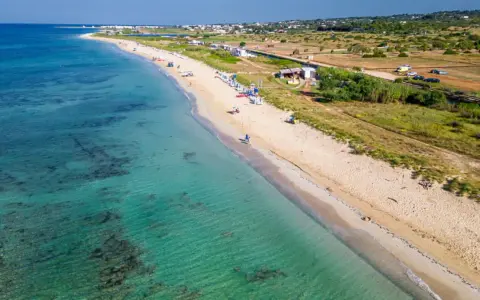 Spiaggia di Torre Vado, Pescoluse, con acque cristalline e sabbia dorata. Un luogo ideale per rilassarsi e godersi il sole.