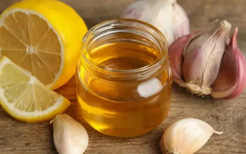Cytryna, miód i czosnek na drewnianym tle.