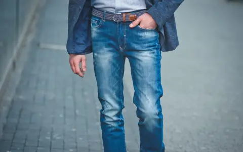 Mężczyzna w eleganckiej marynarce i modnych, przetartych jeansach. Różne rodzaje spodni, od eleganckich po casualowe, pozwalają na tworzenie unikalnych stylizacji.