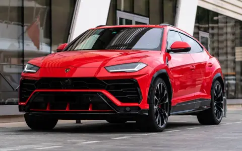 Un imponente Lamborghini Urus rojo, listo para la acción, con su diseño agresivo y llantas negras.
