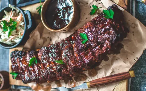 Saftiga spareribs i ugn, glaserade och serverade med en skål coleslaw och BBQ-sås. Perfekt för en härlig middag.