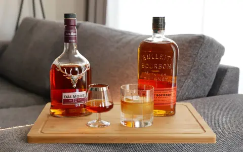 Zwei Flaschen Whiskey, Dalmore und Bulleit Bourbon, und zwei Gläser zeigen die whiskey unterschiede.
