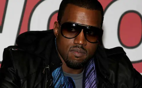 Kanye West w okularach przeciwsłonecznych i skórzanej kurtce, gotowy na koncert w Polsce.