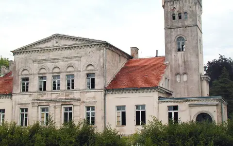Pałac Rekowo, z wieżą i czerwoną dachówką, otoczony zielenią.