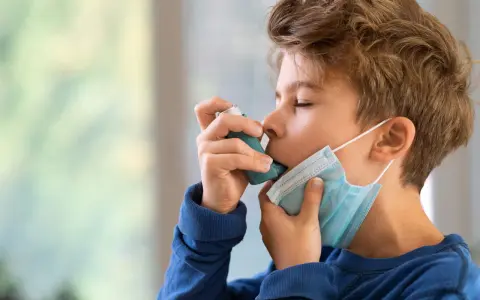 Junge mit Inhalator und Maske. Gute Behandlung beeinflusst die asthma lebenserwartung positiv.
