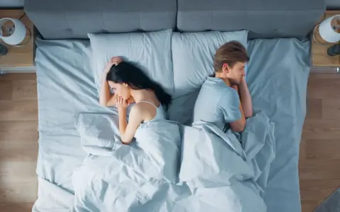 Ein Paar liegt im Bett, jeder auf seiner Seite, die Rücken einander zugewandt. Getrennte Schlafzimmer – der Anfang vom Ende?