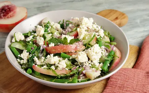 Erfrischender Salat mit Nektarinenstücken, grünen Bohnen, Gurke, roten Zwiebeln und zerbröseltem Feta.