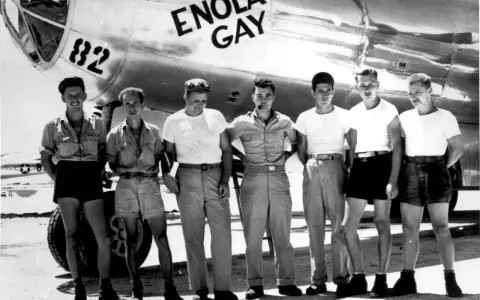 Siedmiu mężczyzn pozuje przed samolotem B-29 o nazwie "Enola Gay".
