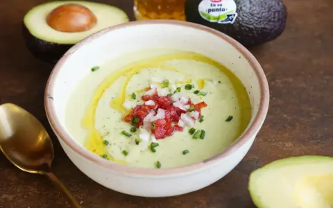 Un cremoso gazpacho de aguacate, coronado con tomate picado, cebolla y cebollino. Un chorrito de aceite de oliva realza su frescura.