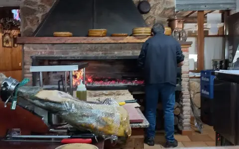 Un hombre trabaja en la cocina del restaurante Emilio Riopar, cerca de un jamonero y un horno de leña.
