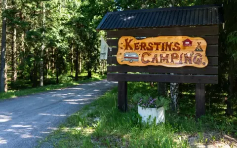 Välkommen till Kerstins Camping! En skylt i trä visar vägen till en lugn plats i skogen.