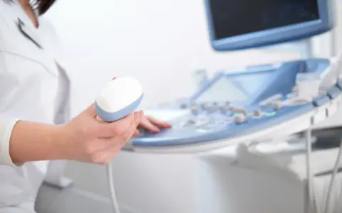 Lekarz trzyma sondę aparatu USG, przygotowując się do badania echo serca. Prawidłowe parametry echo serca są kluczowe dla diagnozy.