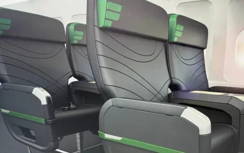 Rows of black airplane seats with green accents. Does Frontier have first class? These seats look comfortable, but it's unclear if they are first class.