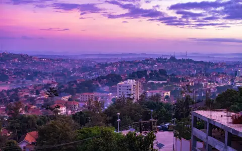 Fioletowe niebo nad krajem z kampalą, z widokiem na wzgórza pokryte zabudowaniami i zielenią.