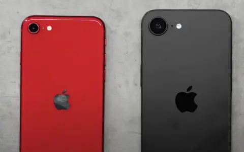 Två iPhones, en röd och en svart, ligger sida vid sida. Den röda har ett Apple-märke och en kamera. Den svarta har också ett Apple-märke och en kamera. Kanske en iPhone SE 4?