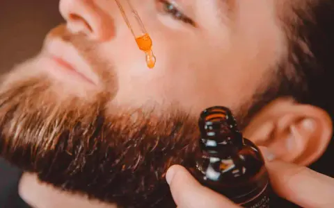 Un hombre aplica aceite con un gotero a su barba. Un secreto para tener una barba bonita y cuidada.