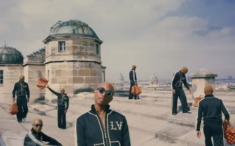 Uomini con tute Louis Vuitton e borse iconiche, un omaggio a chi era Louis Vuitton e al suo impero.