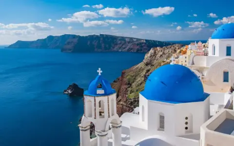 Santorini, Grecja. Białe domy z niebieskimi kopułami na tle morza. Ciekawe miejsca i widoki.