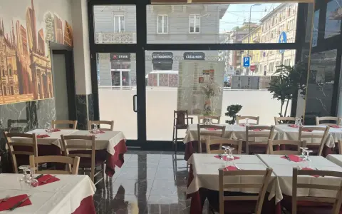 Restaurant interior with tables set for dining, featuring a mural of Milan's skyline.