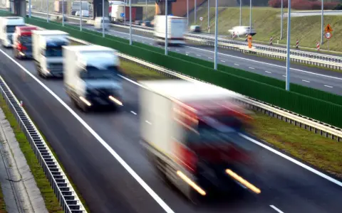 Ciężarówki na autostradzie, rozmyte przez ruch. Kierowcy potrzebują pauzy, by odpocząć od długiej jazdy.