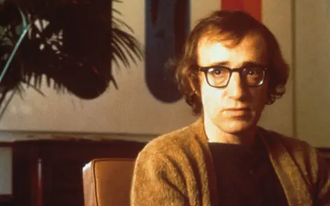 Woody Allen w okularach, w brązowym swetrze. Jego filmy chronologicznie to podróż przez dekady kina.