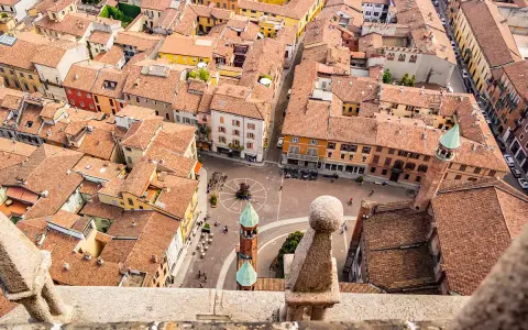Vista aerea di Cremona: tetti rossi, piazze animate e torri. Un assaggio di cosa vedere a Cremona in un giorno.