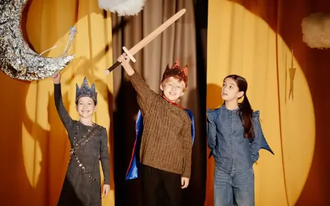 Niños en un escenario, listos para obras de teatro para niños. Uno sostiene una espada, otro una luna y una varita mágica.