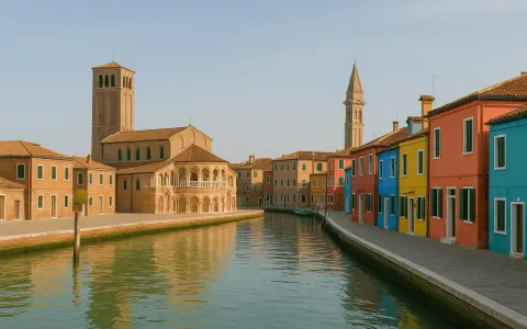Canal bordé de maisons colorées sur l'île de Burano, avec une église et son clocher en arrière-plan.