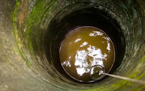Puits profond avec eau trouble, une corde et un seau pour aider à éliminer le fer dans l'eau de forage.