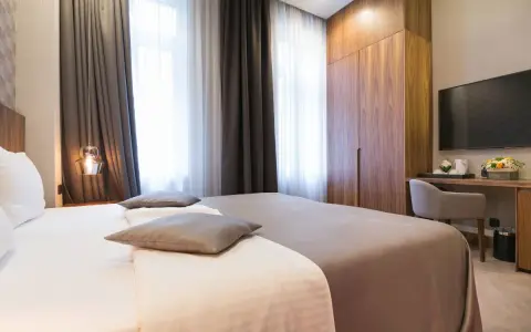 Eleganckie pokoje hotelowe: łóżko, szafa, biurko z TV. Idealne nazwy pokoi hotelowych dla komfortowego pobytu.