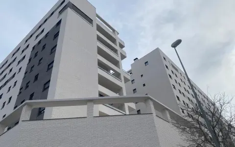 Modernas viviendas VPO en Alicante, edificios de ladrillo blanco y gris con balcones, bajo un cielo nublado.