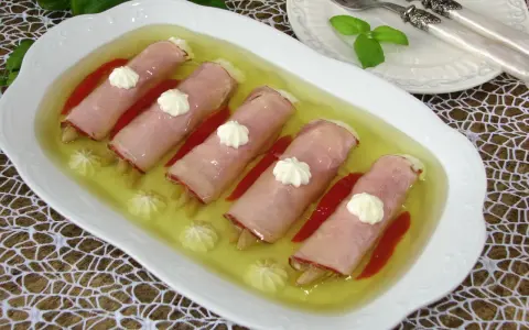 Roladki z szynki z papryką w galarecie, ozdobione kleksami majonezu. Elegancka przystawka na specjalne okazje.