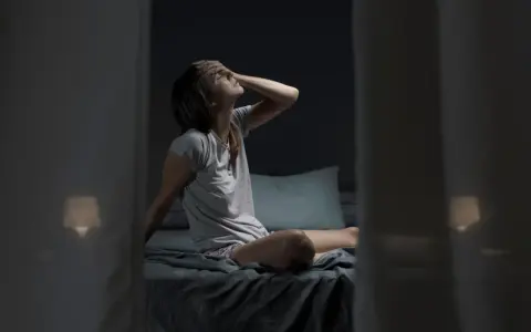 Donna a letto, con la mano sulla fronte, soffre il caldo notturno. Forse il cortisone fa sudare di notte.