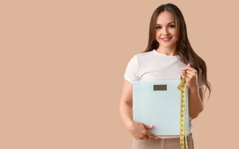 Femme souriante tenant une balance et un mètre ruban, prête à perdre 10 kilos.