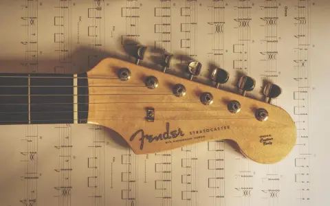 Głowa gitary Fender Stratocaster na tle nut. Idealne nuty na gitarę dla początkujących.