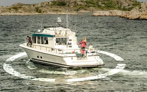 Un bateau navigue en mer, entouré d'une ancre virtuelle. Des personnes sont sur le pont, profitant de la croisière.