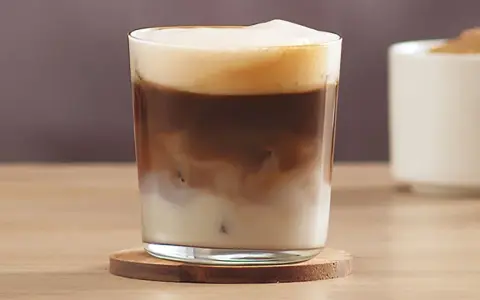 Ein erfrischender kalter Latte Macchiato mit cremiger Schaumkrone und Eiswürfeln.