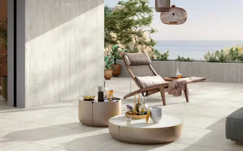 Terrasse en travertin avec mobilier de jardin et vue sur la mer.