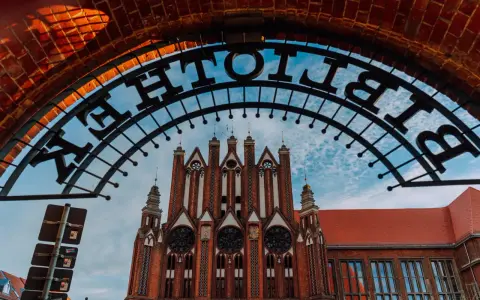 Brama z napisem "Bibliothek" prowadzi do ceglanego budynku w stylu neogotyckim we Frankfurcie nad Odrą.