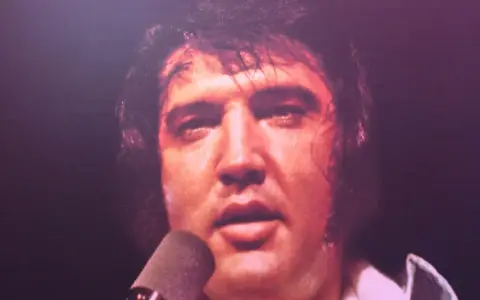 Elvis Presley, sichtlich erschöpft, singt in ein Mikrofon. Ein Moment, der an seinen elvis presley last concert erinnert.