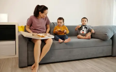 Mama z dziećmi na kanapie, choć jest zakaz słodyczy, wszyscy jedzą pączki.